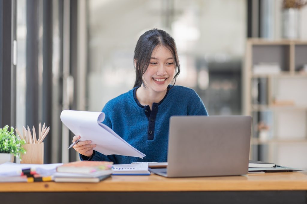 Business Asian woman Using laptop computer and working at office with calculator document on desk,