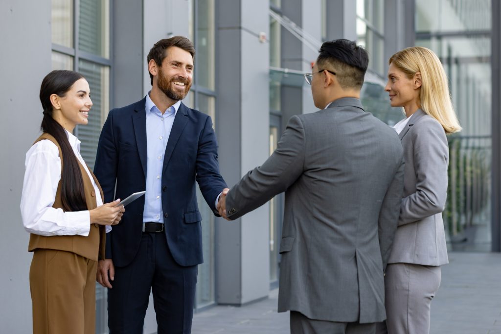 Business meeting of interracial businessmen. Men and women stand outside an office center and shake