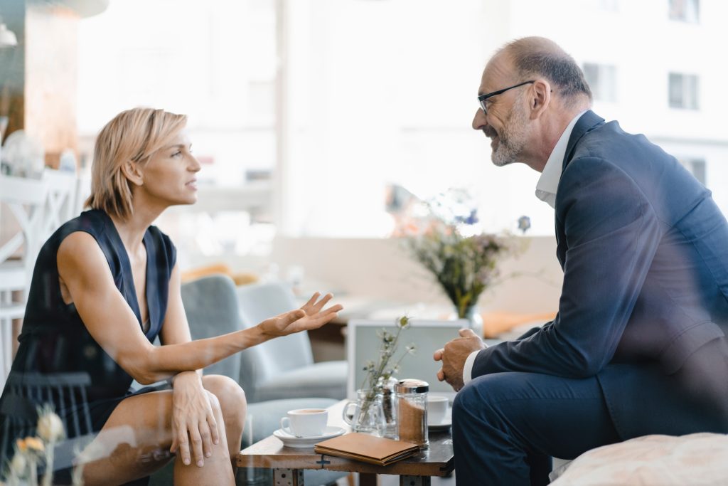 Businessman and woman having a meeting in a coffee shop, discussing work