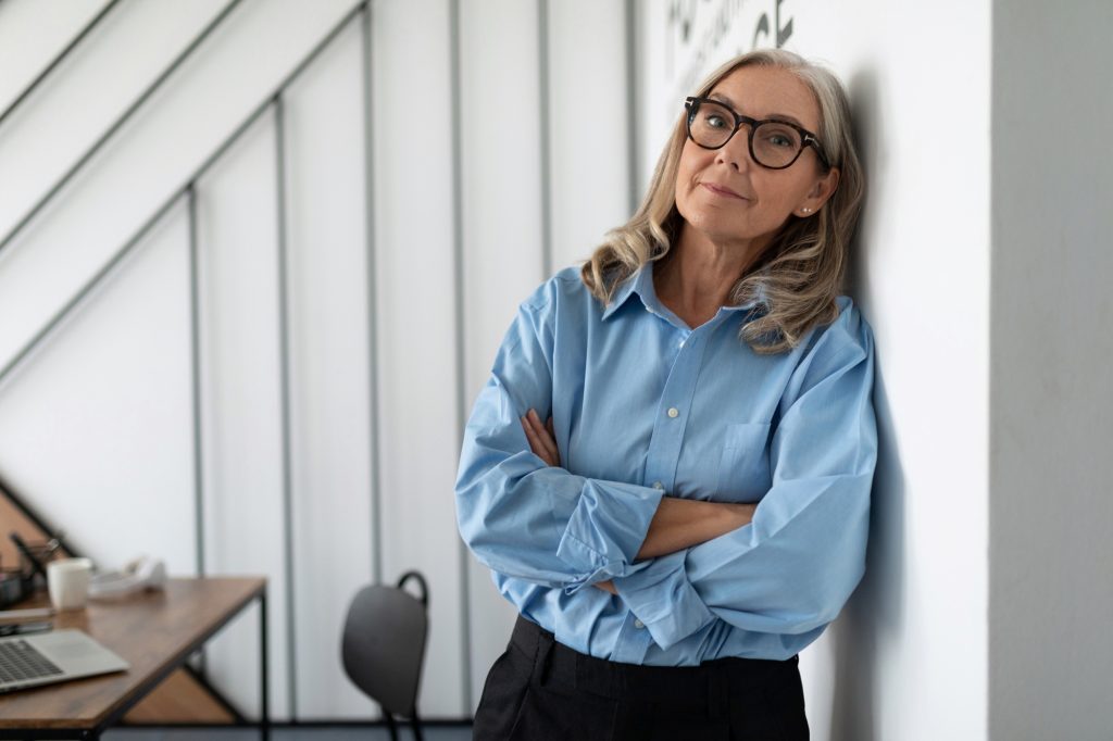 portrait of a successful Middle aged older business woman leaning against the wall in the office