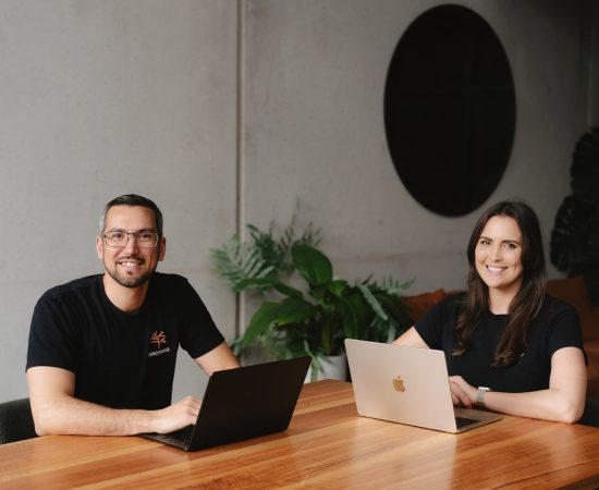 Jared Laidlaw and Nicole Laidlaw from Orchard Financial Marketing sitting at a table with laptops for photoshoot